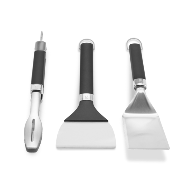 Weber Griddle Grillwerkzeug-Set mit Grillwender, Grillzange und Grillschaber auf grünem Hintergrund