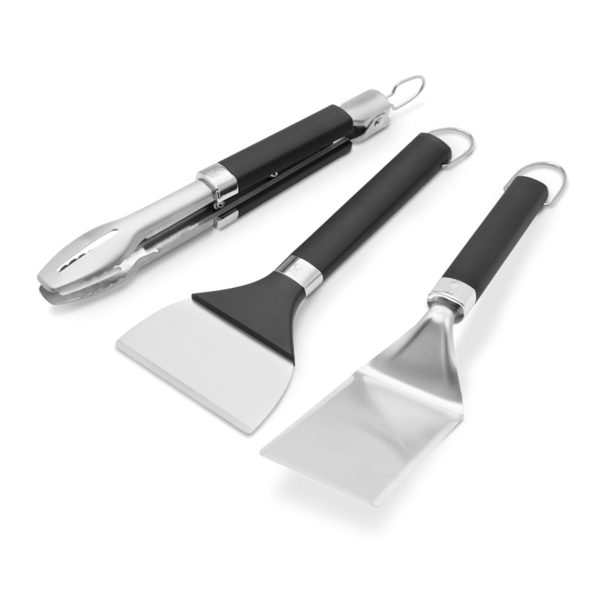 Weber Griddle Grillwerkzeug-Set mit Grillwender, Grillzange und Grillschaber auf grünem Hintergrund
