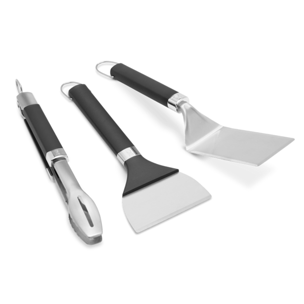 Weber Griddle Grillwerkzeug-Set mit Grillwender Grillzange und Grillschaber auf grünem Hintergrund