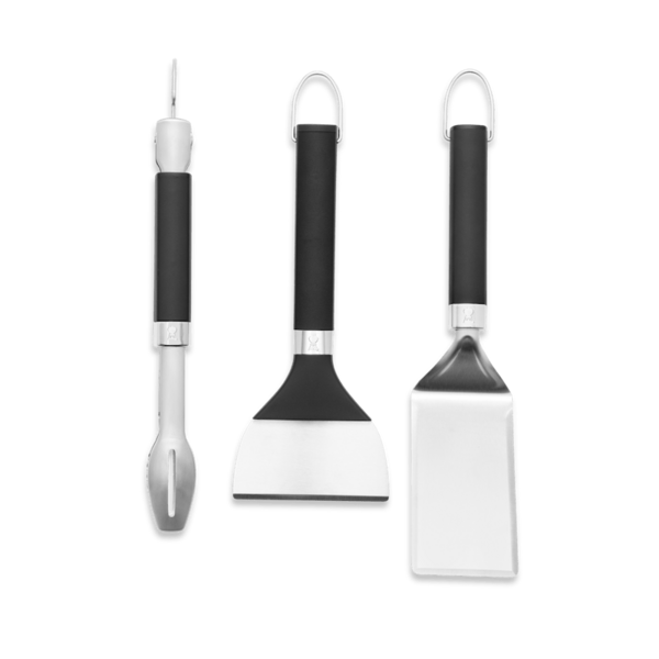 Weber Griddle Grillwerkzeug-Set mit Zange Wender Schaber vor grünem Hintergrund