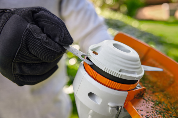 Person in Handschuhen justiert Mähkopf einer STIHL FSA 30 Akku-Motorsense im Garten