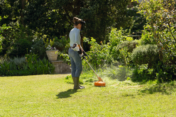 Person verwendet STIHL Akku-Motorsense im sonnigen Garten