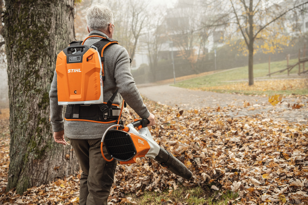 Älterer Mann verwendet STIHL BGA 200 Laubbläser in einem Park mit herbstlichem Laub