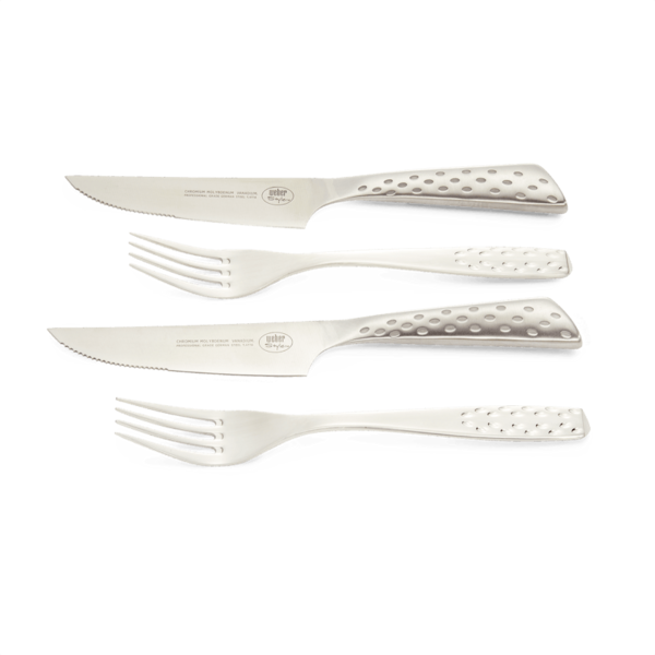 Weber Deluxe Steak-Set mit zwei Messern und zwei Gabeln auf grünem Hintergrund