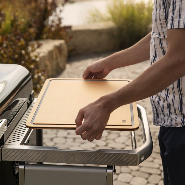 Person platziert Weber Works Schneidebrett auf Grilltisch