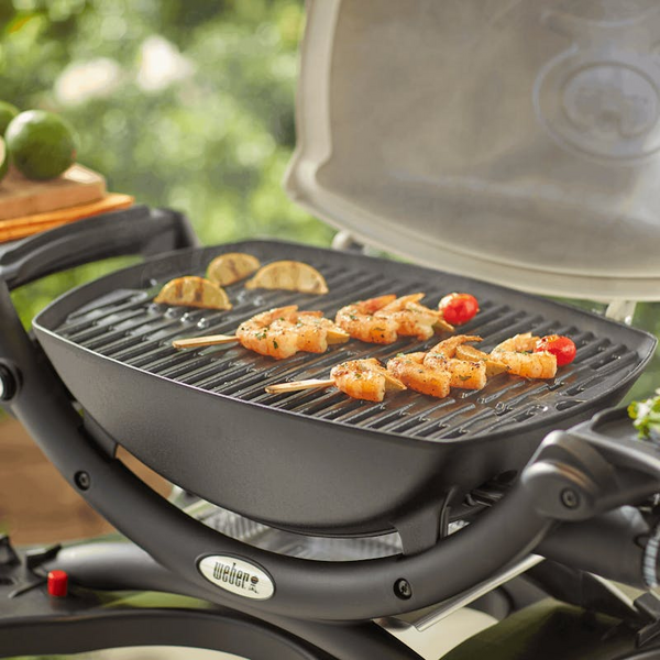 Weber Q1200 Gasgrill mit Garnelen und Tomaten auf Gusseisenrost im Garten