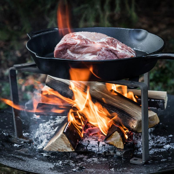 Petromax Feuerpfanne über offenem Feuer mit rohem Fleisch im Freien