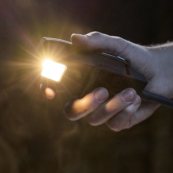Hand hält eine eingeschaltete LED-Lampe im Dunkeln