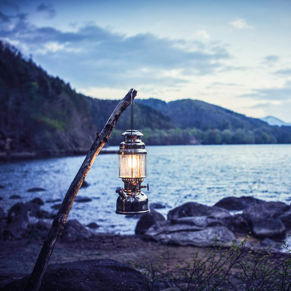 Petromax HK500 Petroleumlampe hängt an einem Ast am Seeufer bei Dämmerung