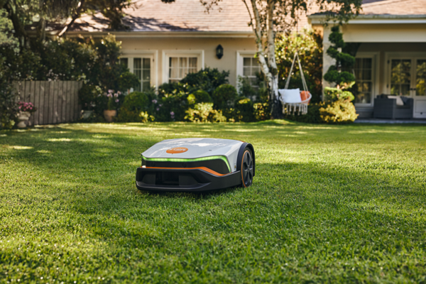 STIHL iMOW 6 Mähroboter mäht Rasen vor einem Einfamilienhaus mit Garten