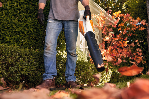 Person verwendet Stihl BGA 57 Akku-Blasgerät im herbstlichen Garten