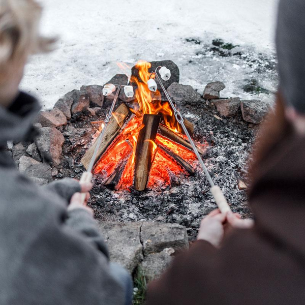 Zwei Personen rösten Marshmallows über einem Lagerfeuer mit Petromax Spießen