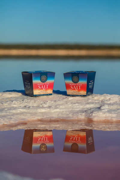 Zwei Packungen Murray River Salt auf salziger Oberfläche vor Wasser und blauem Himmel