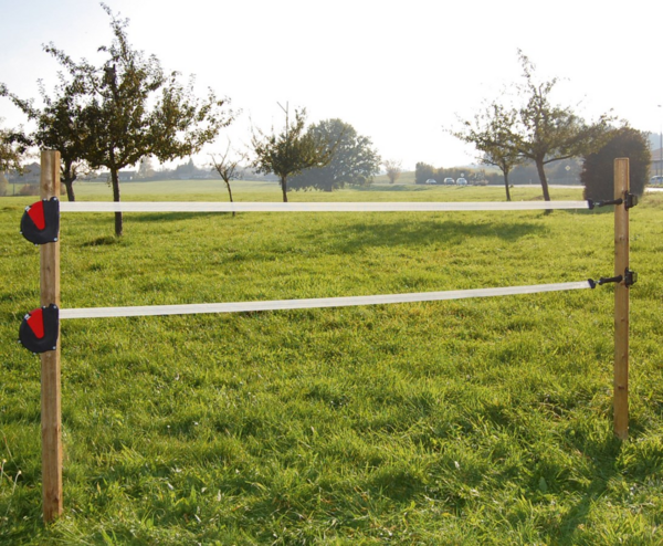 Elektrischer Zaun auf Pferdekoppel mit speziellem Seilanschlusskabel und sonniger Landschaft
