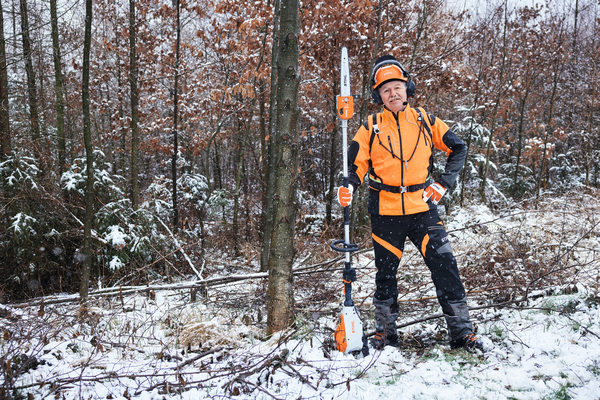 Forstarbeiter in STIHL Schutzausrüstung mit Motorsäge im verschneiten Wald