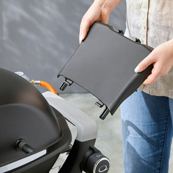 Person montiert abnehmbaren Seitentisch an Weber Gasgrill
