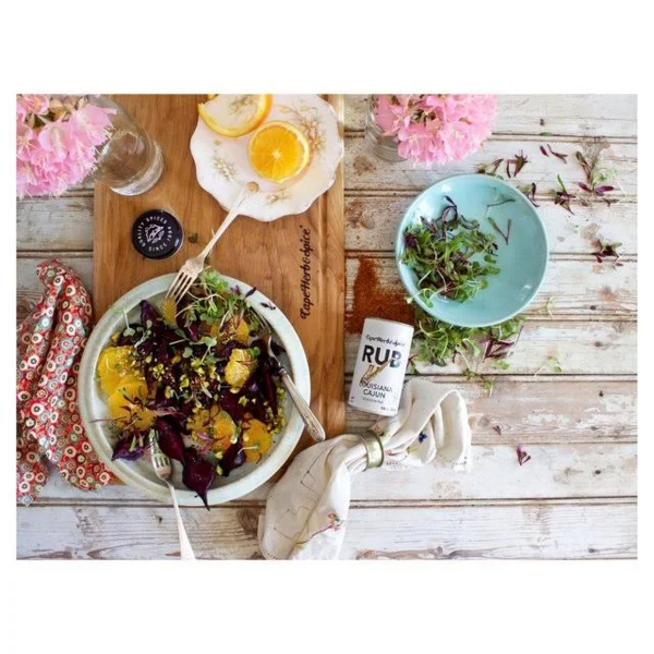Rustikaler Holztisch mit buntem Salat, Cape Herb Rub Louisiana Cajun, Zitrone und Dekoration