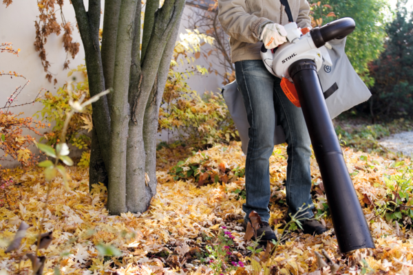 Person verwendet Stihl SH 56 Saughäcksler im herbstlichen Garten