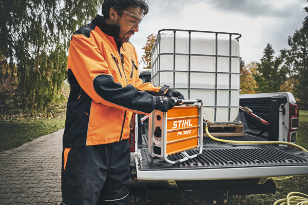 Mann in Arbeitskleidung bedient STIHL PS 3000 Stromgenerator auf Pick-up Truck