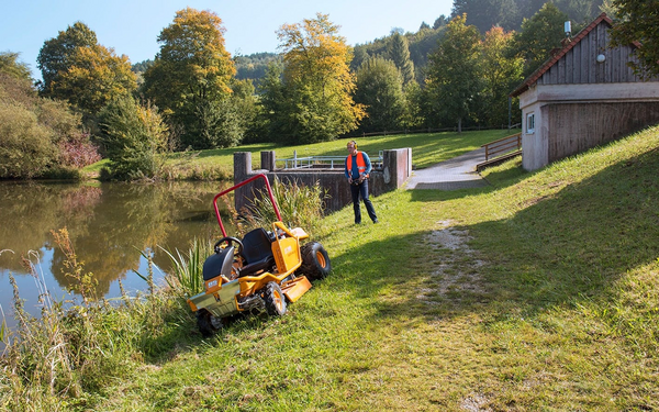 Mann bedient ferngesteuerten Aufsitzmäher AS 940 Sherpa 4WD RC in herbstlicher Landschaft
