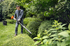 Mann in Schutzkleidung schneidet Hecken mit einem STIHL Heckenschneider in einem grünen Garten