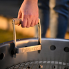Hand hält Petromax Metallgriff bei Sonnenuntergang