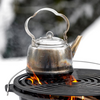 Petromax Teekessel auf offenem Feuer mit sichtbarem Dampf im winterlichen Hintergrund