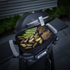 Weber Q3000N Gasgrill bei Nacht mit Grill 'n Go Licht und gegrilltem Essen