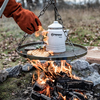 Petromax Perkolator über Lagerfeuer mit Brot auf Grillrost in natürlicher Umgebung