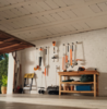 Organisierte Werkstatt mit STIHL Gartenwerkzeugen an weißer Wand und Holztisch