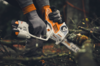 Person verwendet STIHL GTA 40 Motorsäge zum Schneiden eines Astes im Wald