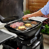 Person bereitet Burger auf Weber Q 2000N Grillplatte im Freien zu