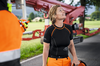 Frau in STIHL Arbeitskleidung mit Helm vor Maschine und grüner Landschaft
