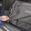 Mann schließt Reißverschluss eines Weber Traveler Kofferraumschutzes im Auto