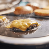 Burger mit geschmolzenem Käse auf Weber Grillplatte