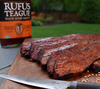 Glasierte BBQ-Rippchen auf Holzbrett mit Rufus Teague Sauce im Garten