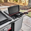 Person entnimmt Grillzange aus integrierter Outdoor-Aufbewahrungsbox an einem Grilltisch
