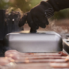 Person hebt Weber Haube auf Grill mit Dampf und gegrillten Speisen