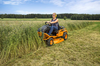 Frau mäht hohe Grasflächen mit orangefarbenem Aufsitzmäher AS 900 Enduro in ländlicher Umgebung