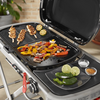Weber Traveler Grill mit Grillplatte voller Gemüse und Hähnchenspieße im Freien