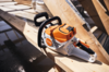 STIHL MSA 160 C-B Akku-Kettensäge auf Holzstapel mit Wassertropfen