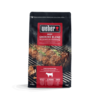 Weber Beef Smoking Blend Räucherchips Verpackung mit Grillfleisch im Hintergrund