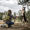 Frau mit Petromax Kühlrucksack spielt mit Hund in der Natur