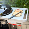 Weber Performer Holzkohlegrill auf Rollwagen mit Seitentisch und Grillzubehör im Freien