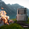 Petromax Kühlrucksack in der Natur neben einem Lagerfeuer mit Bergblick