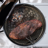 Weber Performer Premium Smart Holzkohlegrill mit gegrilltem Fleisch und glühenden Kohlen