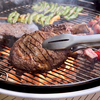 Saftiges Steak auf Holzkohlegrill mit Gemüse im Hintergrund