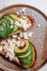 Geröstetes Brot mit Avocado und Feta, bestreut mit Murray River Salz auf rustikalem Teller