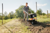 Frau benutzt STIHL MH 445 Motorhacke im Garten bei sonnigem Wetter