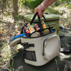 Person hebt Netzeinsatz mit Flaschen aus Petromax Kühltasche im Freien